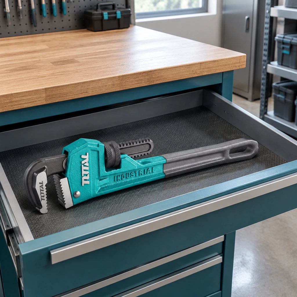 Total 12-inch pipe wrench resting in an organised plant-room service drawer before plumbing work