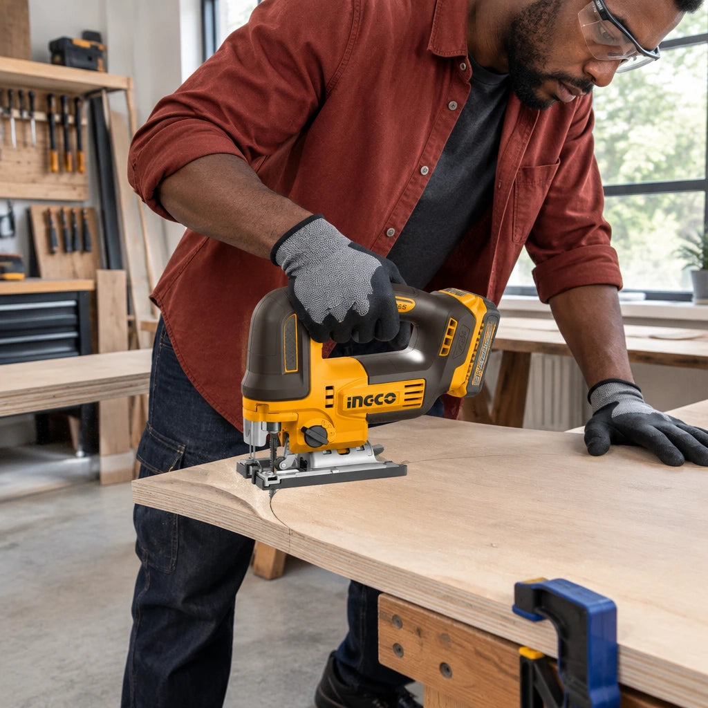 African American cabinetmaker guiding an Ingco cordless jigsaw through a curved plywood cut in a workshop