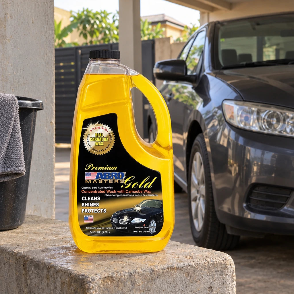 Abro Premium Gold Car Wash bottle resting on a concrete ledge beside a parked car in a Ghanaian carport