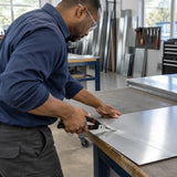 African American sheet-metal technician using Alpro hand snips to cut a straight line in aluminium flashing