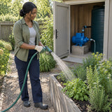 African American gardener waters raised beds from a tap supplied by an Aqua water pump beside a home storage tank.