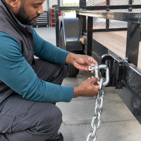 Technician fitting an Atlas D shackle between a chain and stationary trailer restraint eye