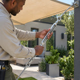 African American installer manually adjusts an Atlas turnbuckle on a cable supporting a courtyard shade structure.