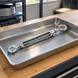 Atlas turnbuckle resting in a hardware tray on an organised professional cable-maintenance workbench.