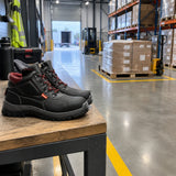 Bellota Classic S3 safety boots resting on a PPE bench beside an organised warehouse staging aisle