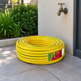Coiled Berry yellow braided PVC garden hose resting in a contemporary residential outdoor utility alcove.