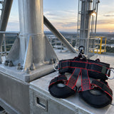 Completed industrial steel support beside a stored Climax Atlas fall-arrest harness after maintenance