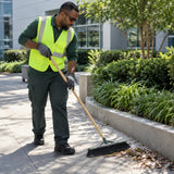 African American grounds worker wearing Climax CLI-597-G dark safety glasses while sweeping a sunny walkway