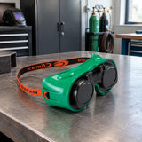 Climax green welding goggles resting on an organised metal-fabrication workbench beside PPE storage