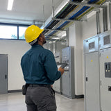 African American facilities technician wearing a yellow Climax 5-RS helmet while inspecting a commercial cable-tray route