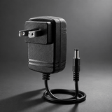 Black power adapter with flat plug blades on a cinematic grey background