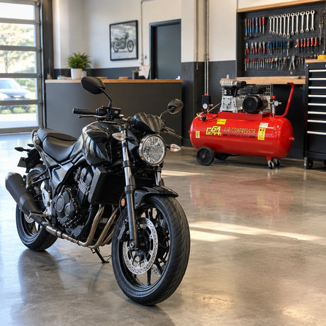Serviced motorcycle ready for collection beside a parked GGA LT100C air compressor in a clean professional workshop.