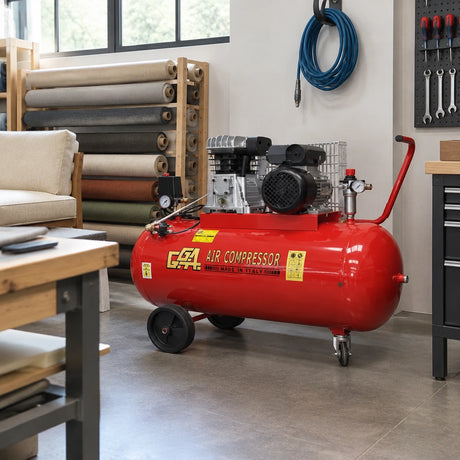 GGA LT200S red air compressor parked in the utility corner of an organised professional upholstery workshop.