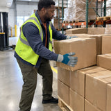 African American warehouse worker wearing Irona leather safety gloves while positioning cartons on a pallet.