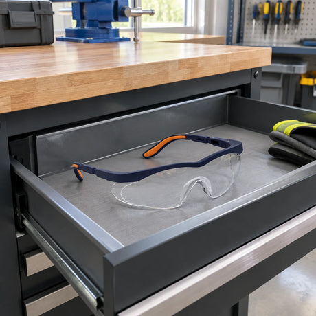 Irona clear safety goggles resting in an open PPE drawer beside an organised fabrication workshop bench