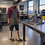 African American fabricator beside a completed steel repair while wearing Irona leather welding leggings