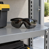 Dark-lens Irona wraparound safety goggles resting in an organised outdoor workplace PPE storage shelf