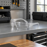 Clear Irona IRO-210-C wraparound safety goggles resting on a PPE shelf in an organised maintenance workshop.