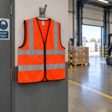 Orange Irona reflective safety vest resting on a wall hook at an organised warehouse dispatch entrance