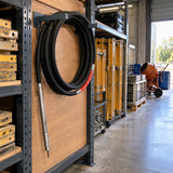 LAE Exen concrete vibrator poker hose stored on a rack in an organised professional contractor equipment bay