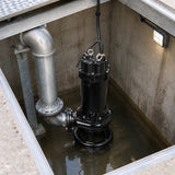 LuckyPro cast-iron sewage pump resting in a wastewater lift-station wet well beside fixed discharge pipework