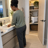 African American resident uses a bathroom basin with steady water while a LuckyPro IVP pump sits in the adjacent utility cupboard.