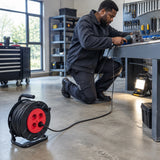African American maintenance technician using a Major four-socket cable reel to power workshop lighting and a corded tool