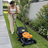 African American homeowner pushes a Marsant 80cc lawn mower along a narrow townhouse garden lawn
