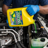 Face-hidden technician pouring ABRO Green Engine Coolant into the coolant reservoir through a funnel