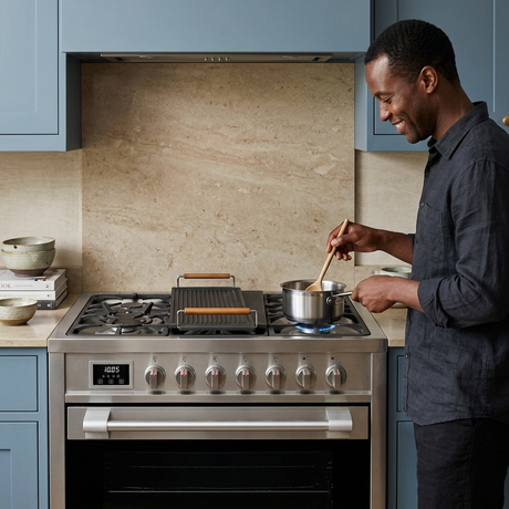 Home cook using the stainless-steel Kaiser Avantgarde Pro range in a blue kitchen
