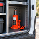 Atlas hydraulic bottle jack stored upright with its pump handle in an organised vehicle-service van.