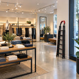 Evenly lit boutique retail display with the folded Mary black steel step ladder resting after ceiling-light maintenance