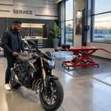 Serviced motorcycle ready for collection beside the inactive Mirage PL-MT06 lift in a clean dealership workshop.