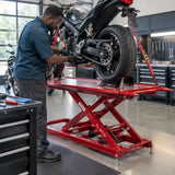 African American motorcycle technician servicing a chain on a raised motorcycle secured on the Mirage PL-MT06 lift.