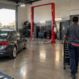 Completed vehicle service bay with a Mirage PL-4.0-2DA lift parked behind a serviced car and open floor for workshop movement