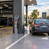 Passenger car ready to leave a modern fuel station after tyre-pressure service, with the Mirage automatic inflator beside the bay.