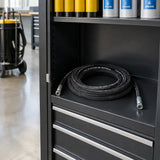 Coiled Mirage replacement grease hose stored in an organised fleet-maintenance workshop cabinet