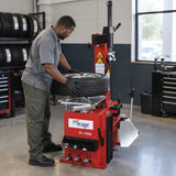 Technician using the Mirage PL-1200 swing-arm tyre changer to fit a passenger-car tyre