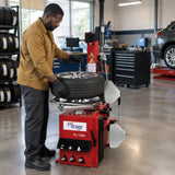 African American tyre technician uses the Mirage semi-automatic changer’s pneumatic bead breaker on a clamped passenger-car wheel.