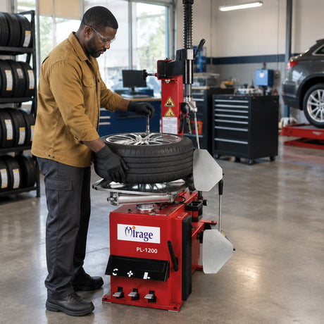 African American tyre technician uses the Mirage semi-automatic changer’s pneumatic bead breaker on a clamped passenger-car wheel.