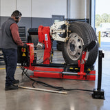 African American truck-tyre technician using the Mirage PL-2900 hydraulic changer to remove a tyre from a heavy vehicle wheel