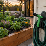 Freshly watered residential garden bed with the green adjustable spray gun resting beside the hose