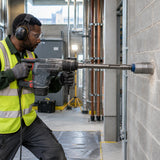 Building-services installer uses a Mister SDS-Max adapter for deep core drilling through a blockwork plant-room wall