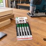 Packaged NRG T244D curved-cut jigsaw blades resting on an organised joinery workshop bench