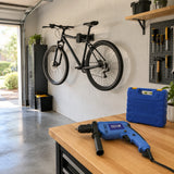Completed wall-mounted bicycle rack holding a bicycle in an organised garage, with the Pirana percussion drill resting nearby.