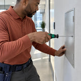 Facilities technician using a Wera Phillips screwdriver to secure a wall service cover