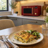 Finished browned vegetable gratin served beside a closed Bordeaux Red Kaiser Empire microwave in a contemporary kitchen