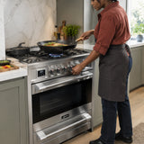 African American home cook using the Kaiser five-burner gas cooker’s turbo burner and wok support to prepare vegetables and noodles.