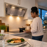 Finished meal and settled cooktop beneath the Kaiser stainless steel built-in cooker hood in a calm contemporary apartment kitchen.