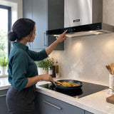 African American home cook using the Kaiser AT 6433 Eco touch controls while sautéing vegetables beneath the stainless cooker hood
